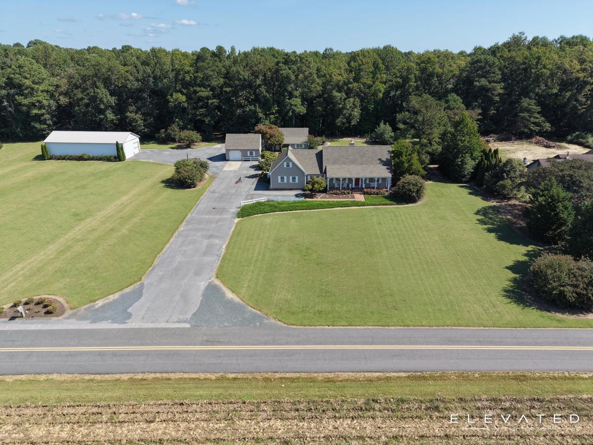 Gray Cape Cod home with a long paved driveway and wide lawn